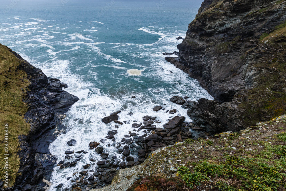 Obraz premium view from the top of the hill, the rocky coastline and the white water foam, the rocky mountains off the coast and the horizon