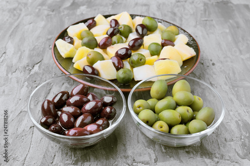 glass bowls with green and black olives, on gray rustic stage