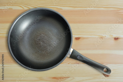 Scratches on the old teflon frying pan on wooden floor, top view