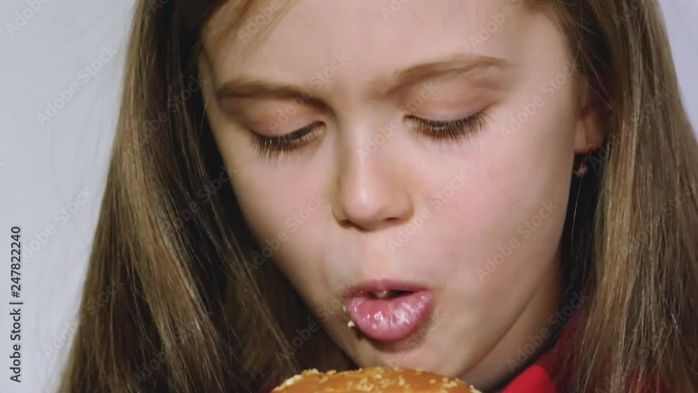 The girl eats a hamburger with pleasure The girl eats a hamburger with pleasure