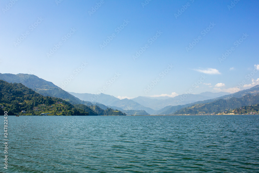 view from the lake to the green mountain valley under the blue sky