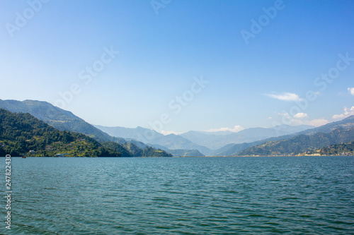view from the lake to the green mountain valley under the blue sky © Pavel