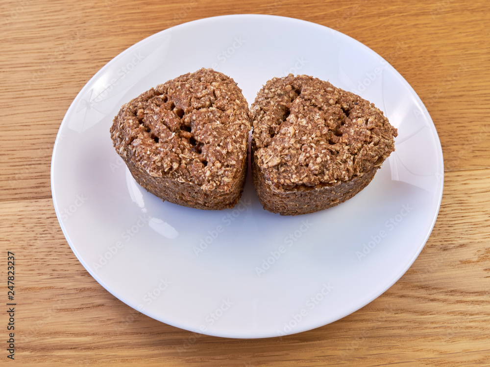 A white plate standing on a wooden table on which there are Two slices of homemade bread. A white plate standing on a wooden table on which there are Two slices of homemade bread.
