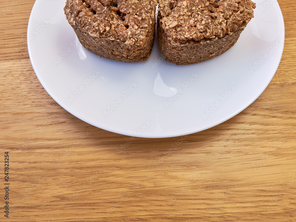 A white plate standing on a wooden table on which there are Two slices of homemade bread. copy space A white plate standing on a wooden table on which there are Two slices of homemade bread. copy space