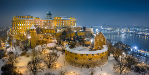 Budapest, Hungary - Aerial view of illuminated Buda Castle Royal Palace on a winter night with snowy park and Szechenyi Chain Bridge