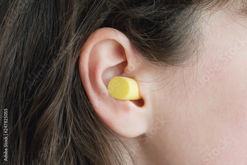 Woman's ear with an ear plug, noice  reduce, noice pollution . photo