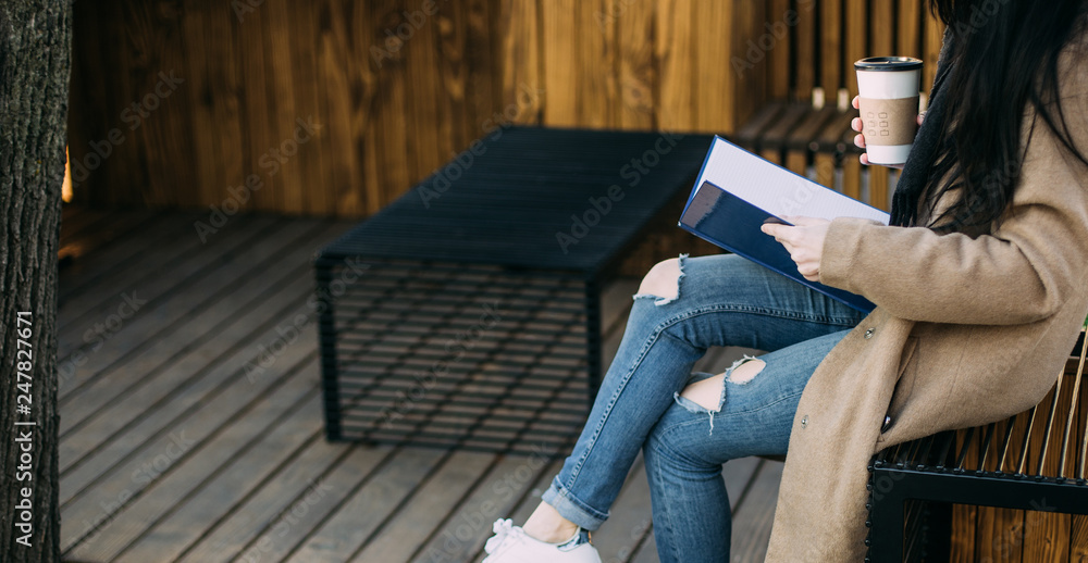 Young woman in warm coat with book, coffee and laptop study on wooden place