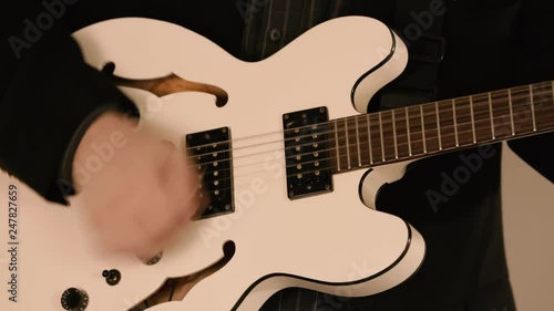 Male musician playing a white guitar