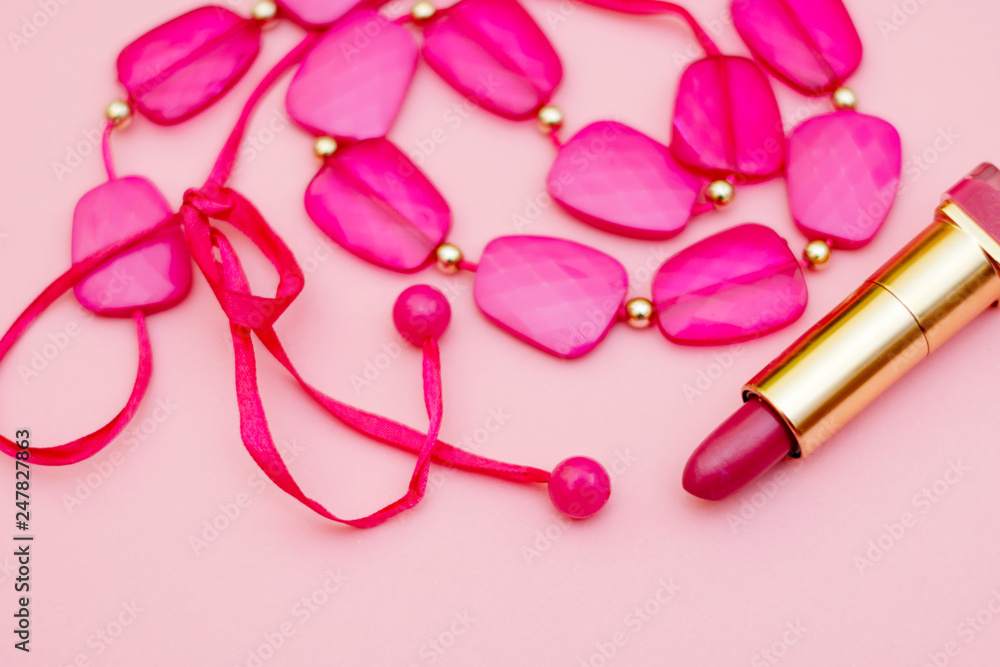 Fashionable pink accessories - beads, lipstick, belt on a gentle pink background. flay lay.