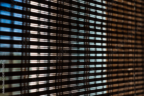 The interior of the home, sunlight shining through the bamboo blinds at the window.