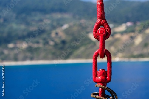 links of an old lifting sling of red color closeup on an indistinct natural background photo