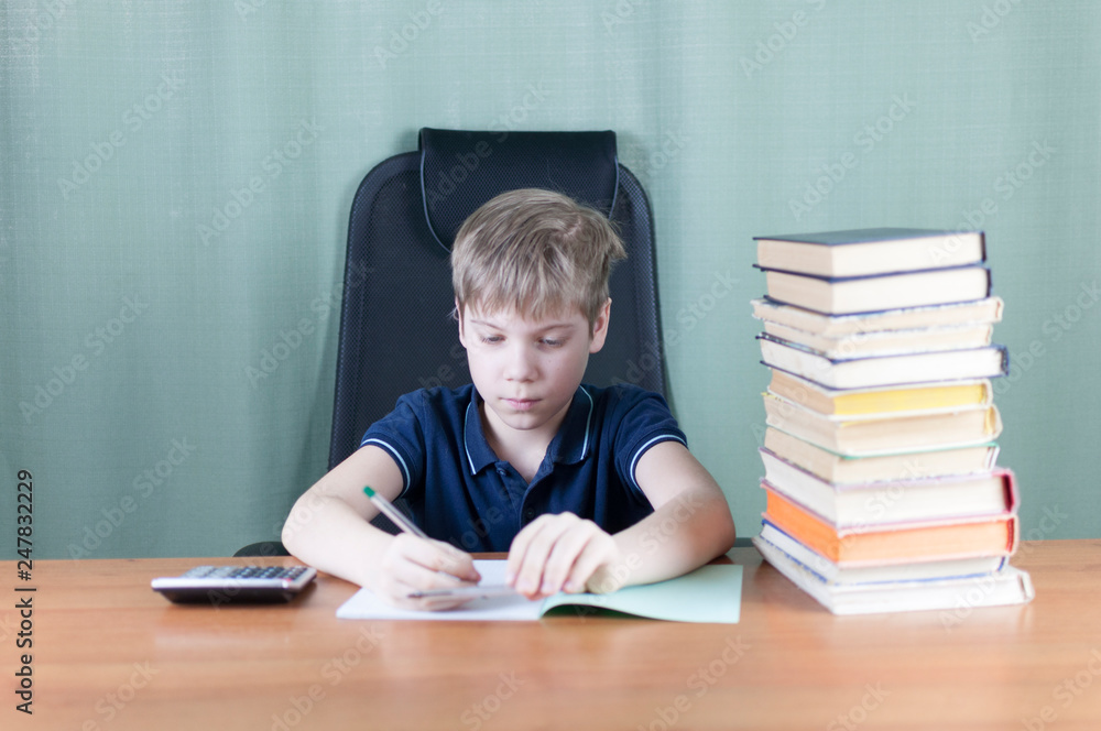 A young boy is working on his homework at the table. Back to school concept. Idea and creativity concept. Copyspace A young boy is working on his homework at the table. Back to school concept. Idea and creativity concept. Copyspace
