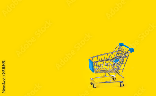 Shopping trolley on yellow background and some copy space.
