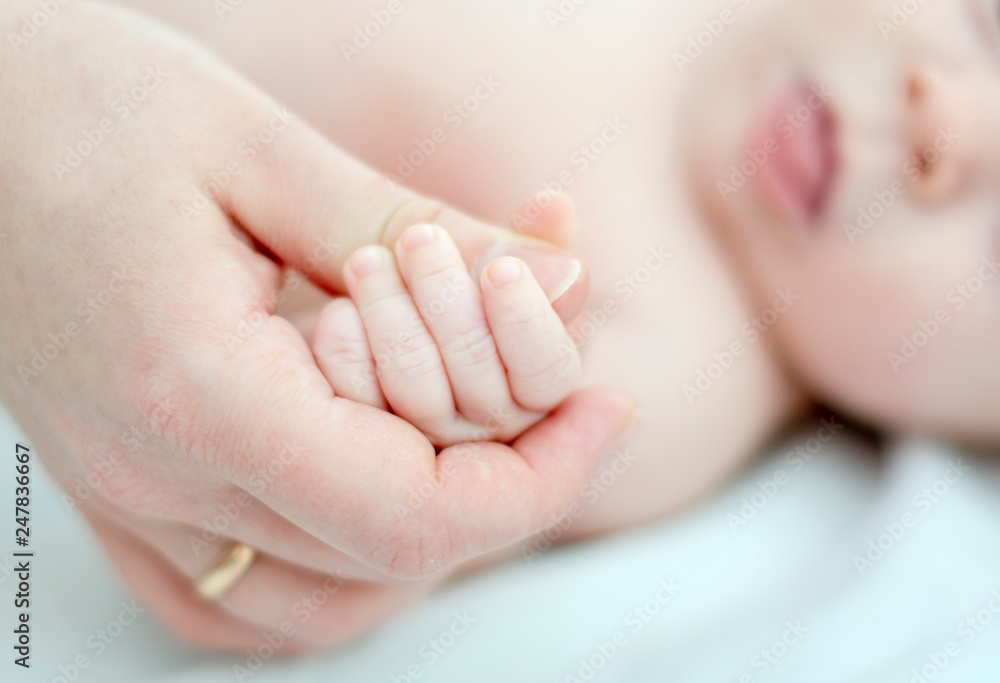 the little baby lies on her back and holds the mom's hand with the little wrinkled handle. light key the little baby lies on her back and holds the mom's hand with the little wrinkled handle. light key