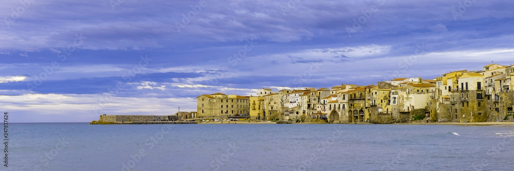 Houses along the shoreline and cathedral in background Cefalu Sicily. Italy.