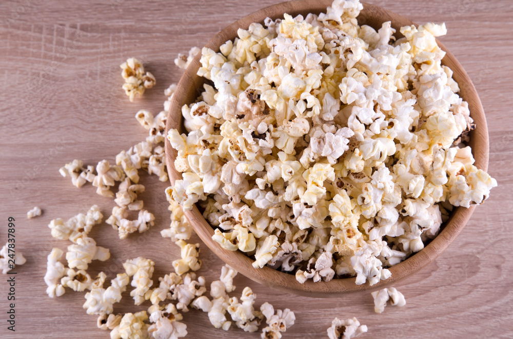 popcorn in a wood cup and on a wood table at a dark background popcorn in a wood cup and on a wood table at a dark background