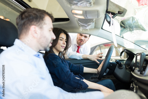 Female Customer Examining Car Interiors With Boyfriend