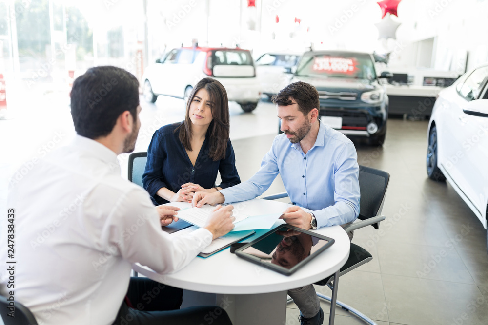 Mid Adult Couple And Seller With Car Purchase Terms Mid Adult Couple And Seller With Car Purchase Terms