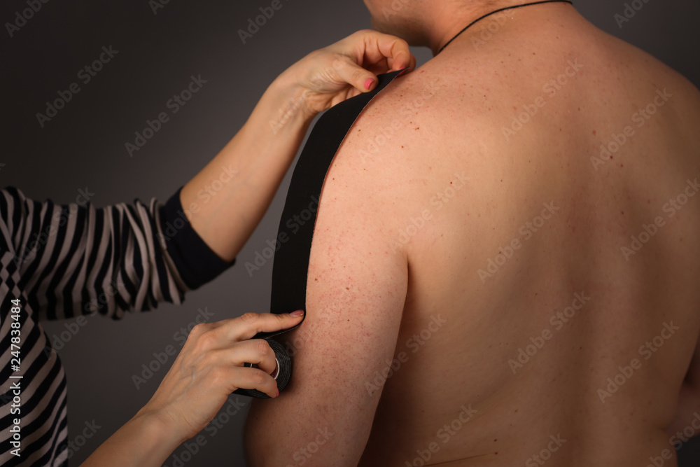 Fototapeta premium woman puts tapes on arm of ordinary man, Taping