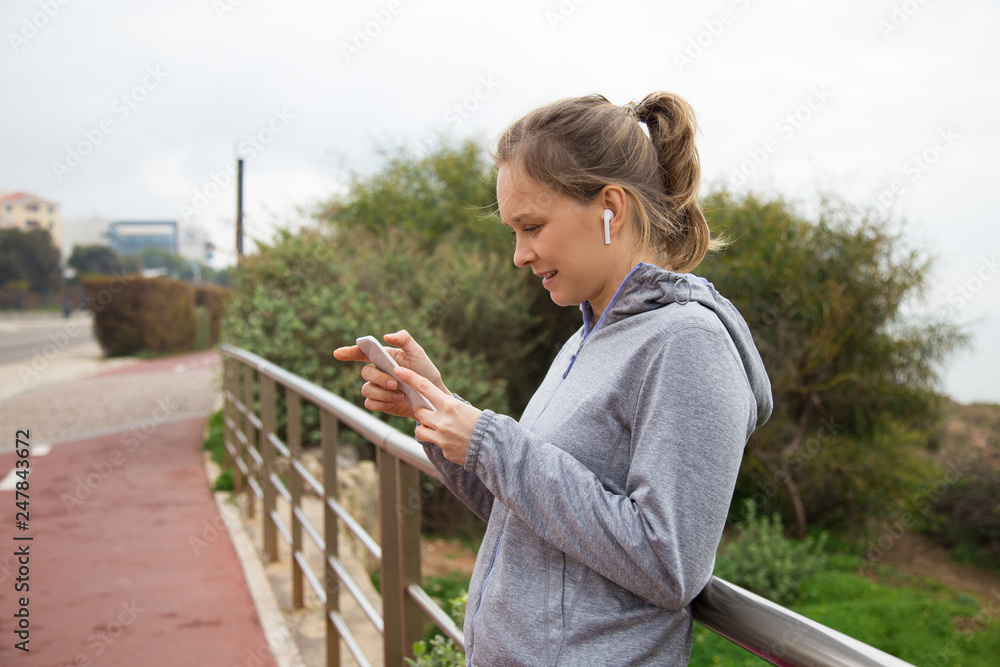 Joyful sporty girl stop jogging and checking up app Joyful sporty girl stop jogging and checking up app
