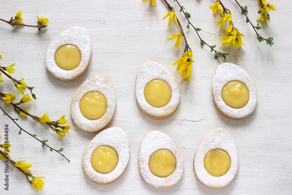 Homemade Easter lemon cookies and forsythia blooming twigs on a light background.