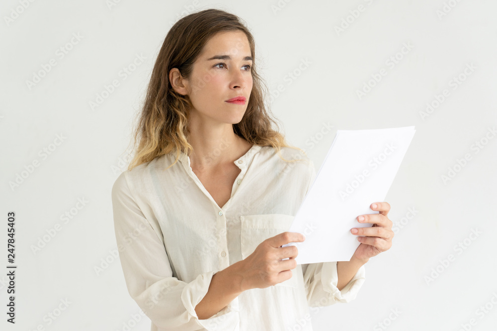 Thoughtful young woman holding sheet of paper Thoughtful young woman holding sheet of paper