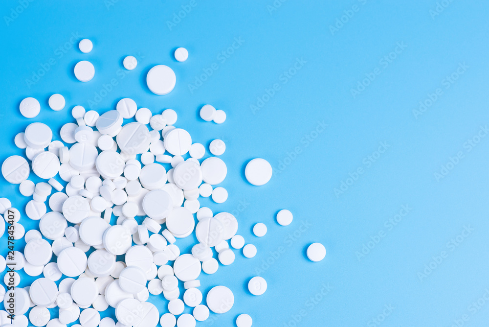 White pills or capsules on a blue background White pills or capsules on a blue background