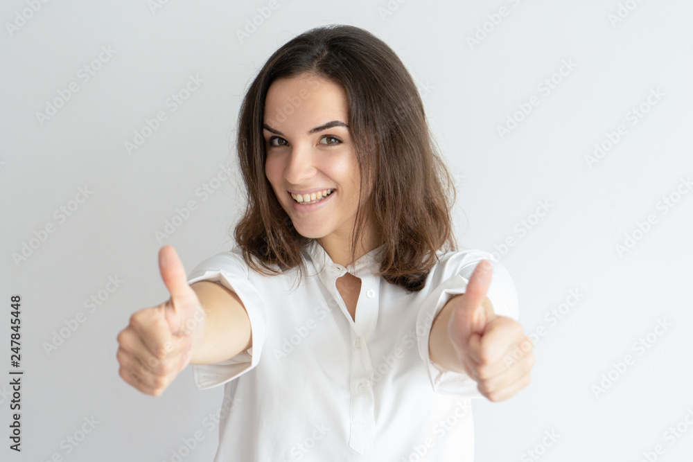Cheerful young lady showing thumbs up and looking at camera Cheerful young lady showing thumbs up and looking at camera
