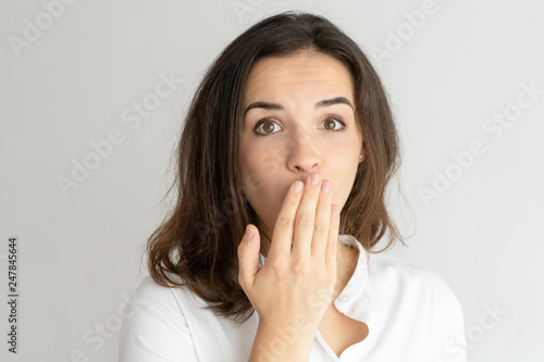 Embarrassed young woman covering mouth with hand