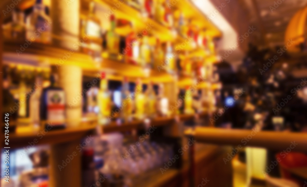 Blur a bottle of alcoholic drink on the shelves in club pub or bar against backdrop of dark party. Brightly lit bottles of expensive whiskey and brandy are not sharply blurred bokeh night restaurant