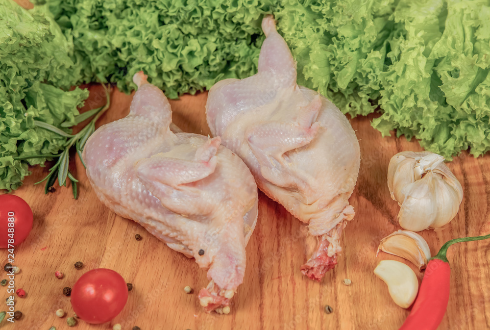Two fresh chicken on a cutting board with tomatoes, lettuce, garlic, pepper, onion Two fresh chicken on a cutting board with tomatoes, lettuce, garlic, pepper, onion