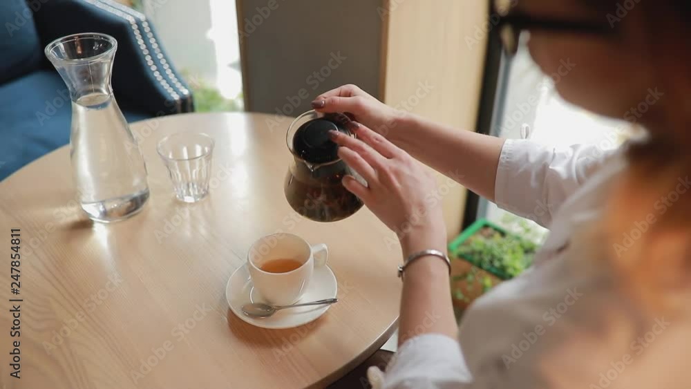 Woman pours tea into cup sitting in a cafe and drinks it, top view, slowmotion Woman pours tea into cup sitting in a cafe and drinks it, top view, slowmotion