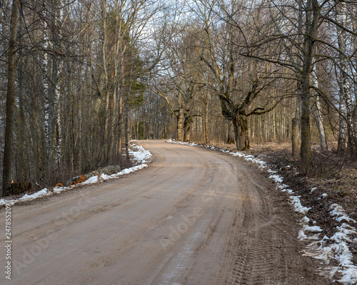 empty country gravel road with mud puddles and bumps