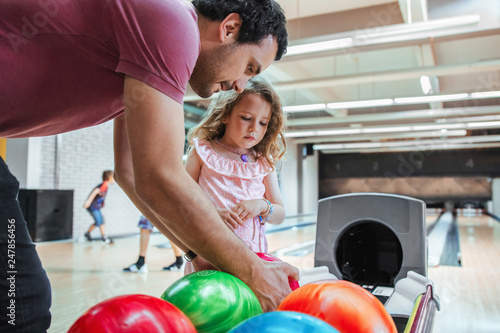 Father and daughter having fun at bowling alley. Choosing a ball color.