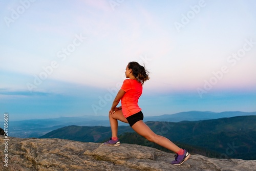 Woman cross country runner stretching in mountains