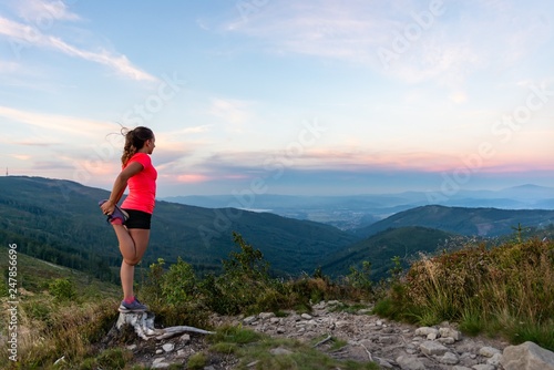 Woman cross country runner quads stretching in mountains at summer
