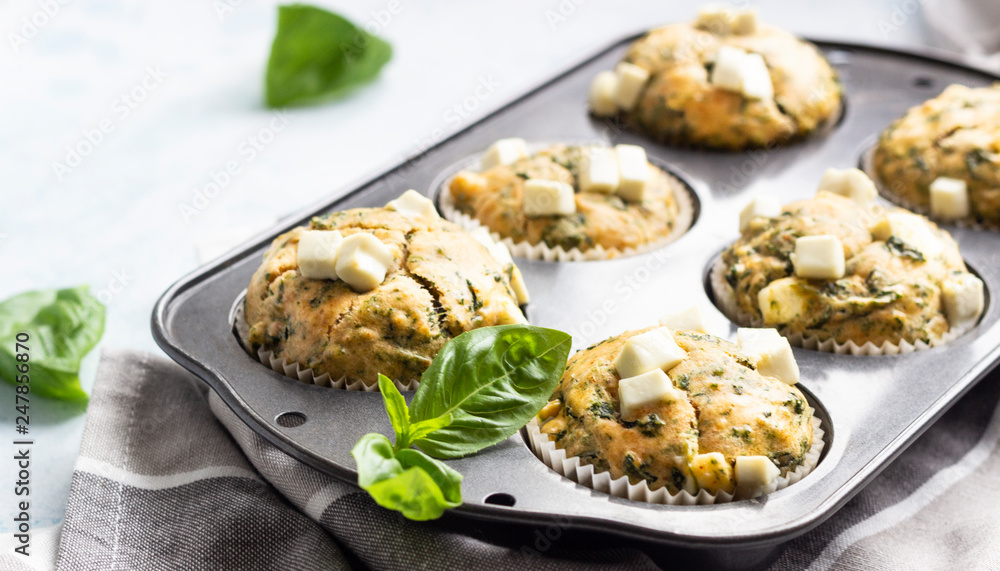 Muffins with spinach and feta cheese in a muffin tin. Light background. Copy space. Muffins with spinach and feta cheese in a muffin tin. Light background. Copy space.