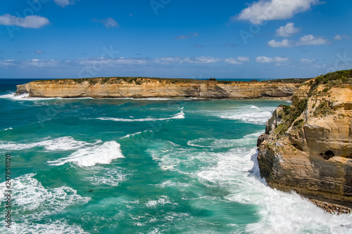 An ocean scene with blue-green water and orange rocks and cliffs. On the Great Ocean Road, Victoria, Australia.