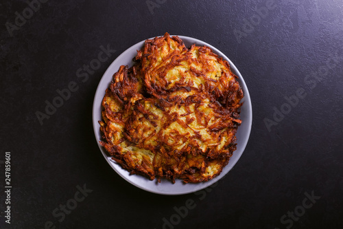 Fotografie Hash brown and sour cream on a plate on a dark stone background, well fried