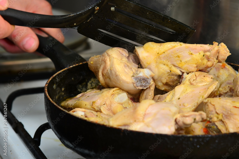 The cook mixes fried chicken in a pan with butter and spices. The cook mixes fried chicken in a pan with butter and spices.