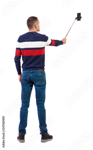 back view of standing young guy with smartphone in the hands of.