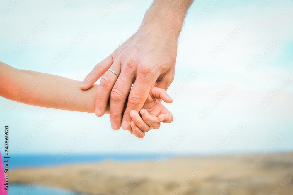 Beautiful hands of parent and child on sea background Beautiful hands of parent and child on sea background
