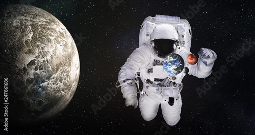 Single giant astronaut in outer space near tiny Earth and Mats and moonlike planet. Elements of this image were furnished by NASA.