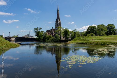 St Alban's English Church located next to the citadel Kastellet in Copenhagen, Denmark. Small lake in from of the church. Reflection in the water. Bright, sunny day.