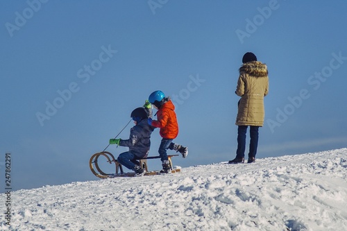 dzieci zjeżdżające z górki na sankach w obecności rodzica © Jarek Witkowski