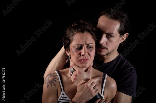 man threatening a scared woman with bruises and wounds on her face in a gender violence case in a young couple