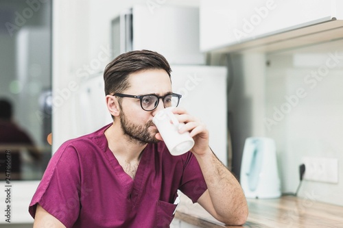 young doctor drinks coffee, tea from a cup after working in a medical office.
