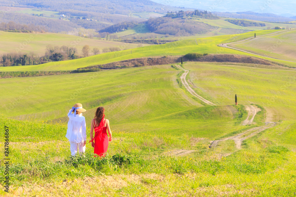 Ragazze camminano in una strada tra le verdi colline