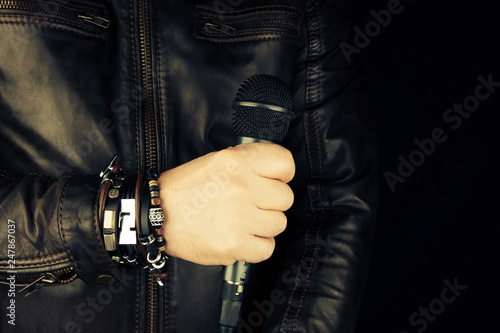 Man hand holding microphone. Leather bracelet and accessory .Hard rock, heavy metal,gothic and punk style.Brutal jacket