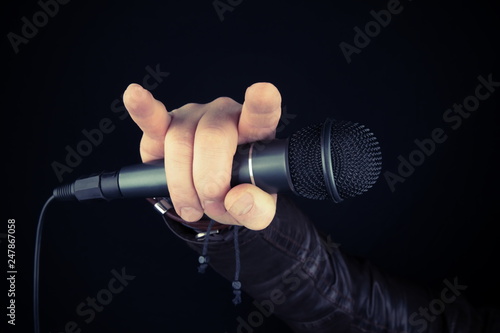 Man hand holding microphone. Leather  bracelet and accessory .Hard rock, heavy metal,gothic and punk style.Brutal jacket